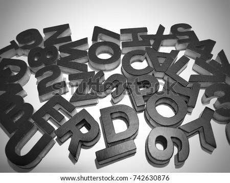 Black 3d letters and numbers in random order on white surface.