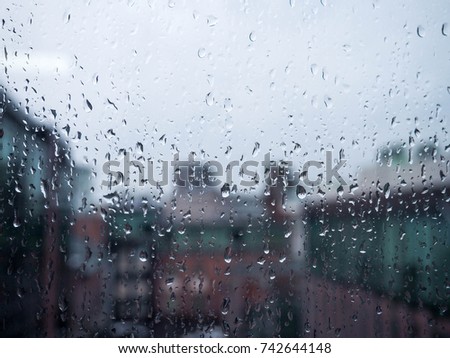 Drops of rain on dirty glass background, city cars through the rain on the window
