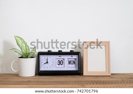 frame photo with clock and plant on wooden shelf