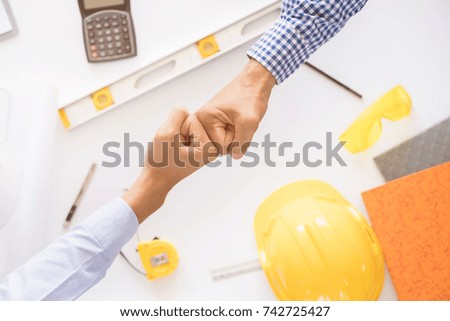 Top view of asian construction engineer joining hands with architect after finish meeting about  develop a plan house at construction site, business colleagues teamwork concept