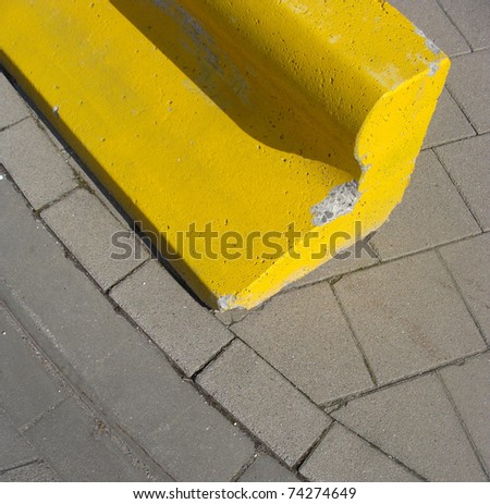 yellow concrete block on the sidewalk to protect pedestrians from cars