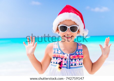 Little girl in Christmas hat on white beach during Xmas vacation
