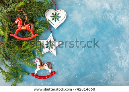 Christmas and New Year blue background with fir branches and Christmas toys - horses, a star and a heart. Top view