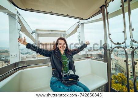 Beautiful girl taking picture at Ferris wheel on her phone, autumn