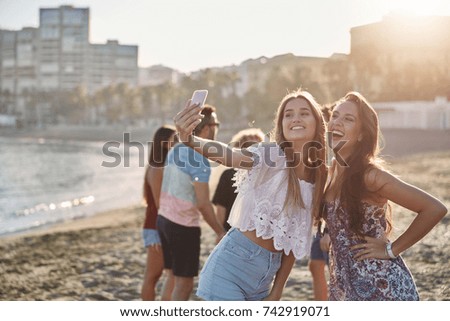 Two happy girls posing to selfie on beach