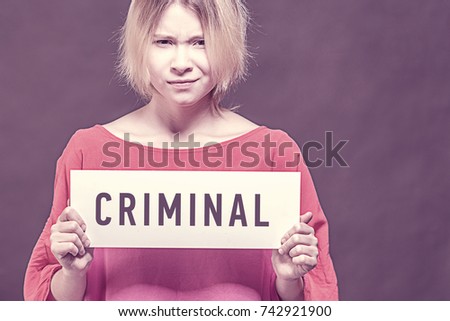 Blonde girl teenager in a red blouse holding a poster with an inscription CRIMINAL