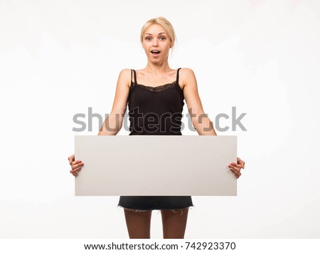 Young surprised woman portrait of a confident businesswoman showing presentation, pointing placard gray background. Ideal for banners, registration forms, presentation, landings, presenting concept.