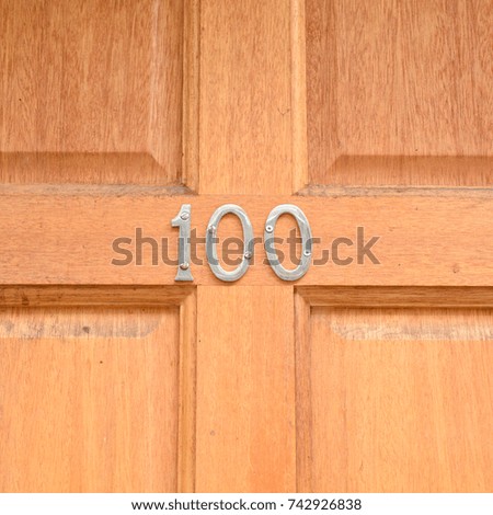 House number 100 sign on wooden door