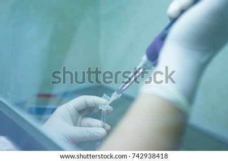 soft focus scientist holding syringe and blur dropping bacteria to it in laminar flow hood