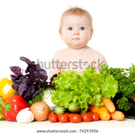 The babe in an environment of the fresh vegetables, isolated on the white