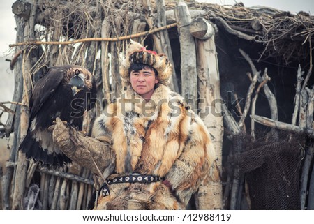 Mongolian eagle Hunters in traditionally wearing typical Mongolian Fox dress culture of Mongolia on Altai Mountain background at Ba-Yan UiGII, MONGOLIA