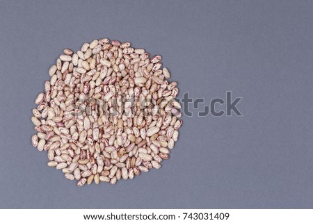 A pile of beige in speck of beans on a gray background. Multicolored kidney beans