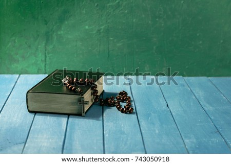 Bible crucifix and beads on a blue wooden table. Beautiful background.Religion concept.