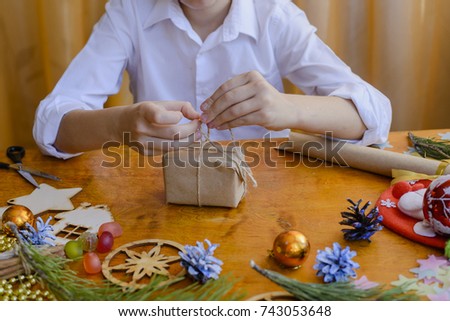 preparing for the new year and Christmas, beautiful gift wrapping, a boy 8 years of making holiday gifts Royalty-Free Stock Photo #743053648