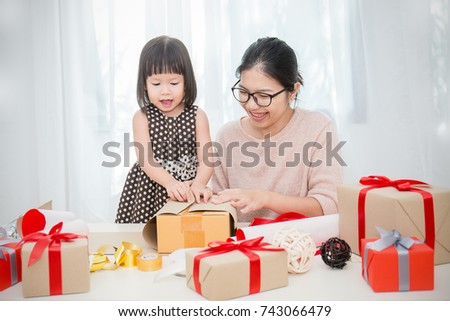 Asian little girl help her mother wrapping gift box, celebration holiday christmas mother'?s day concept.