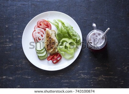 A fresh meal of chicken fillet with vegetables and tasty juice on a dark wooden background