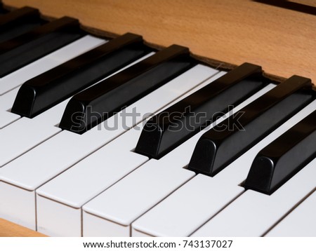 Closeup of piano keys of a light brown piano