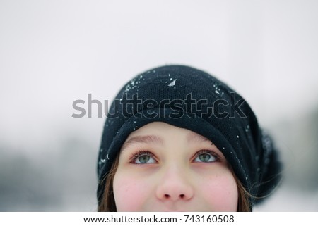 girl's eyes are looking up. Girl in a black beret. A child with beautiful green eyes against the background of a winter landscape.