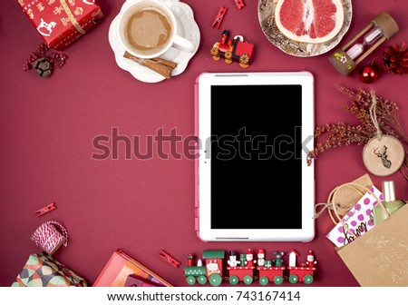 computer tablet on red background with christmas presents and coffee
