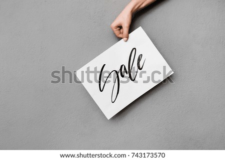 Close up photo of woman hand holding modern postcard on gray background