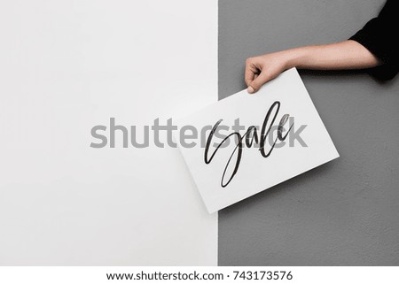 Close up photo of woman hand holding cool postcard on gray background