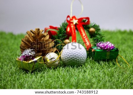 Golf ball with Christmas Gift with pine cone on green grass