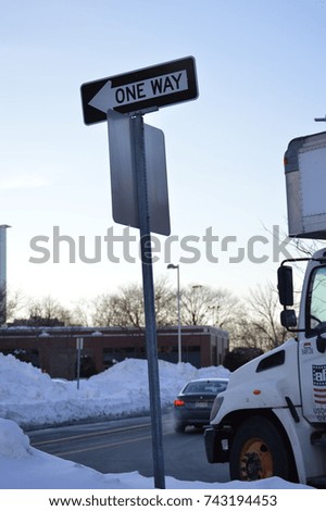 one way signal sign road street direction to a certain place or location during the winter weather holidays with the front of a white truck 