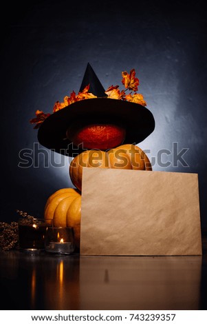 a composition for decorating a house for halloween, orange pumpkins, a big black witch hat and burning candles
