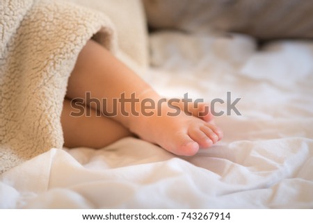 Cute baby feet wrapped in a blanket. Happy Family, new baby, concept. Cozy morning, joyful moments at home. Selective focus.