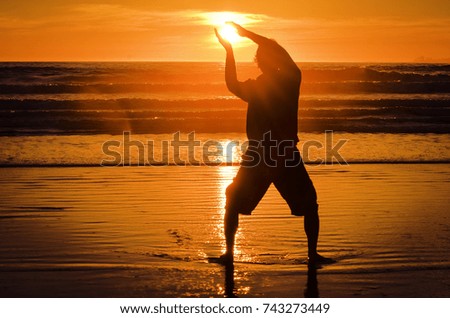 Man in silhouette holds the sun at sunset