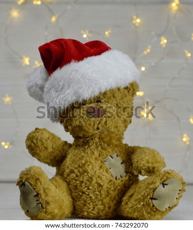 Teddy bear mascot dressed in a Santa Claus hat.