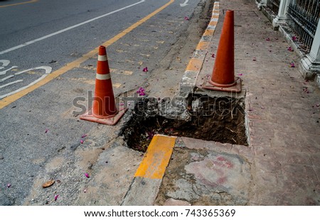 Plastic orange cone at the pothole on asphalt road