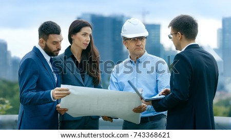 Team of Investors, Developers and Engineers Discuss Future of the Major Real Estate Project  with Major Contractor while Consulting Drafts and Plans. In the Background Big City with Skyscrapers. Royalty-Free Stock Photo #743368621