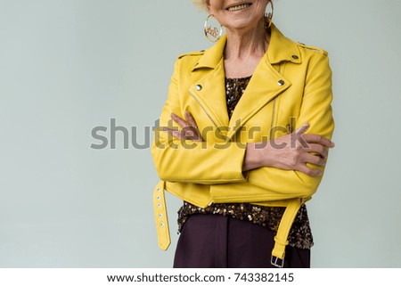 cropped view of fashionable senior woman in yellow leather jacket and yellow sunglasses, isolated on grey