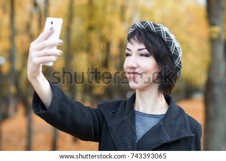 girl taking selfie in autumn city park, yellow leaves and trees, fall season