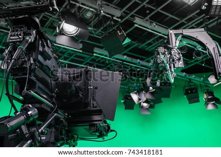 Broadcast television studio camera in virtual green screen studio room with LED lights on the ceiling.