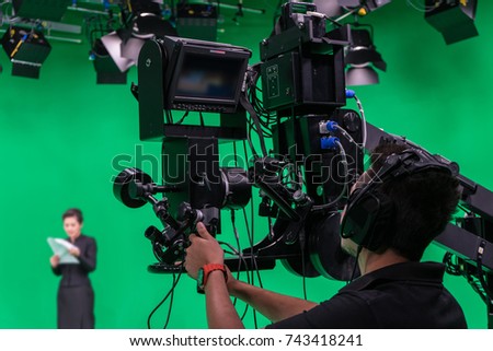 Cameraman and announcer working in a broadcast television virtual green screen studio room.