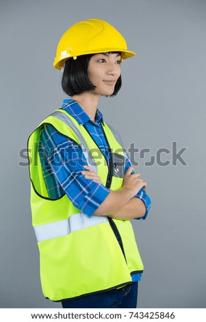 Smiling female architect standing with arms crossed against grey background
