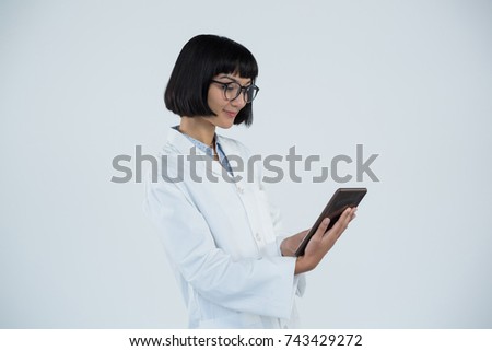 Smiling doctor using digital tablet against white background