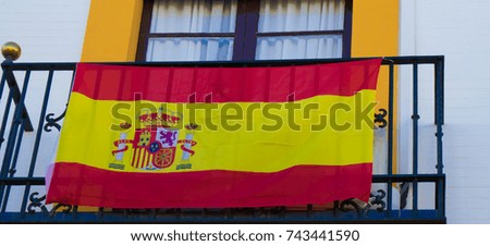 The national flag of Spain  hang on the balcony in a street  .