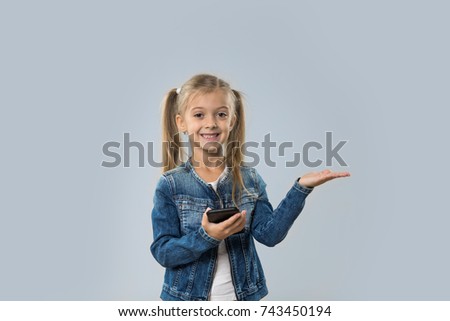 Beautiful Little Girl Using Cell Smart Phone Happy Smiling Open Palm To Copy Space Isolated Over Gray Background
