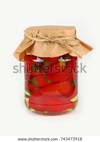 Close up of one glass jar of pickled red hot cherry chili pepperoncini peppers with kraft paper parchment decoration and twine over white background, low angle side view