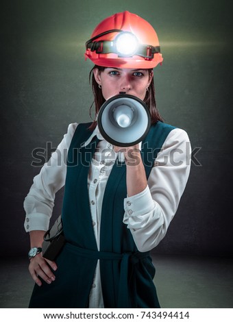 Business woman with a loudspeaker and a helmet mine. Studio shoot. Mining cryptocurrency concept