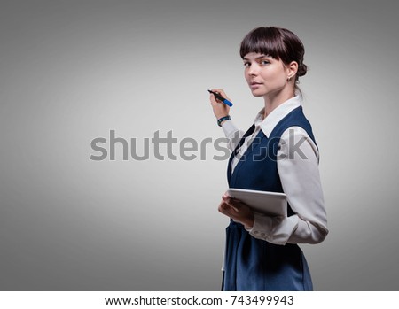 Smiling business woman holding tablet on gray background. Studio shoot