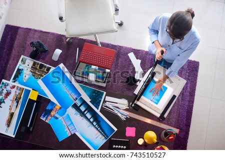 Young people and small business. Busy woman at work as photographer in lab. Beautiful girl cropping, cutting color prints for photo exhibition. Artist and art profession.