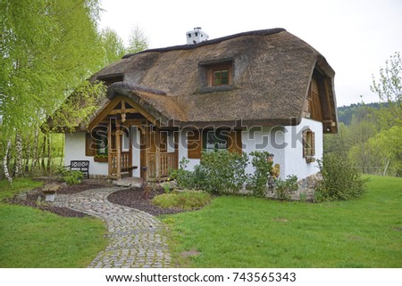 Poland, country house with straw roof and garden in front of home. Royalty-Free Stock Photo #743565343