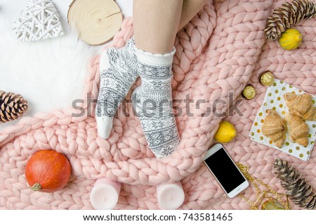 Flatlay Girl legs in a warm socks on background of Merino wool handmade knitted large blanket, trendy concept. Close-up Autumn and winter mood flatly