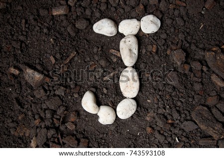 English alphabet (J - alphabet) from the white rock on the soil