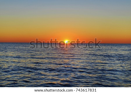 Landscape with sunset over the sea between the waves. Royalty-Free Stock Photo #743617831
