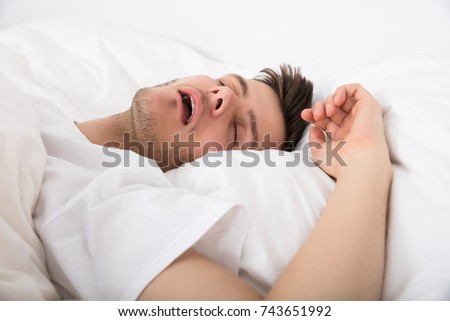 View Of Tired Young Man Snoring While Deep Sleeping In Bed Royalty-Free Stock Photo #743651992